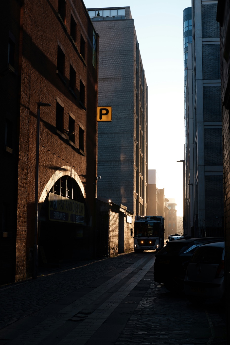 A narrow urban alley lit by low sun
